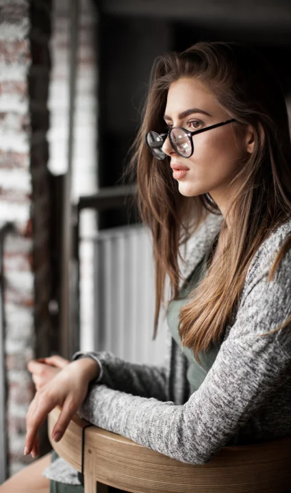 A woman seated on a chair, elegantly dressed in a luxurious fur coat.