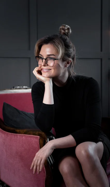 A woman seated on a chair, elegantly dressed in a luxurious fur coat.